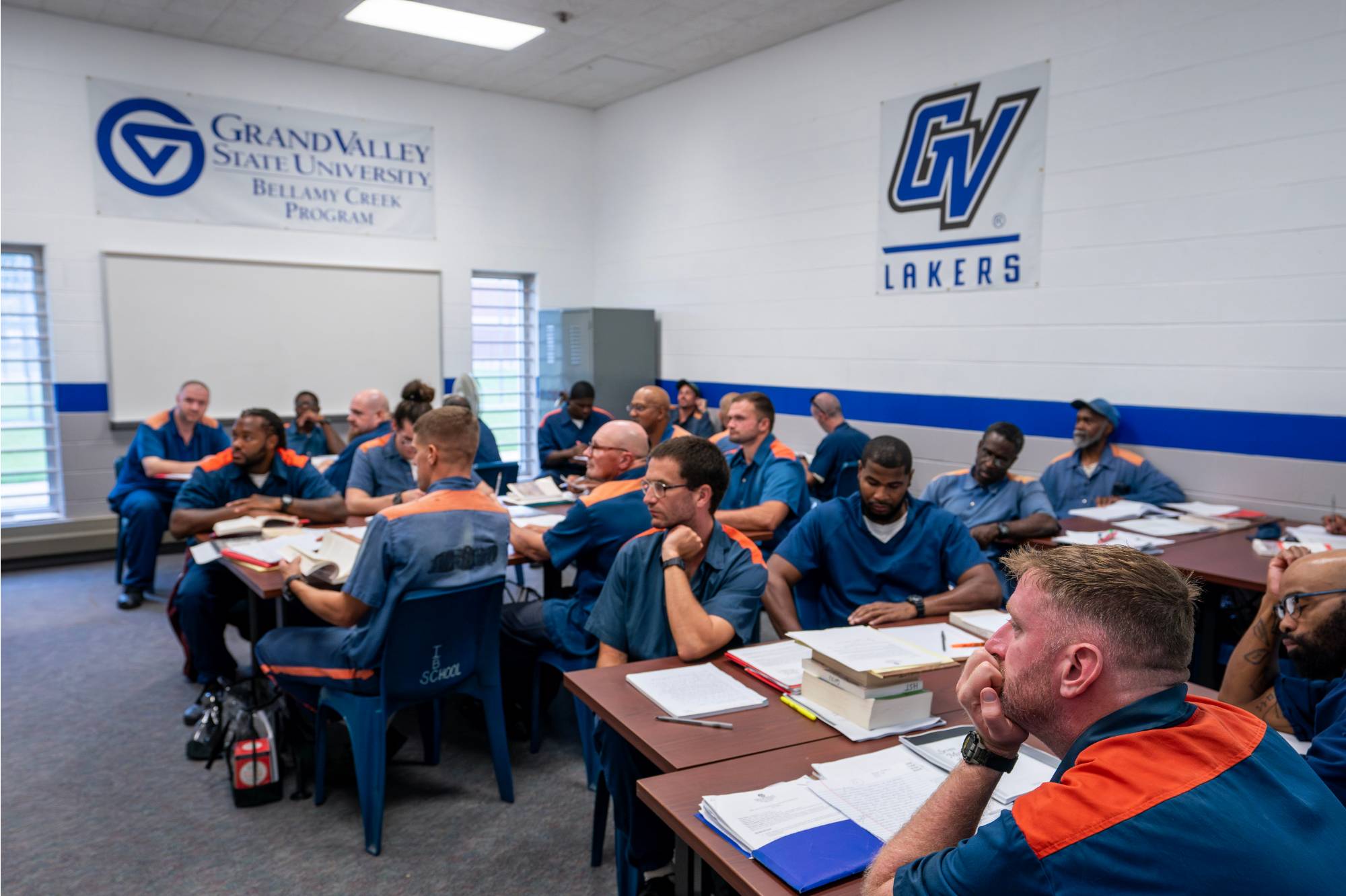 Students sitting at desks in a classroom with GVSU banners on the wall behind them.